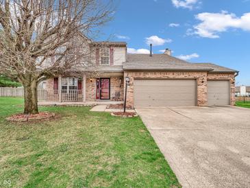 Charming two-story brick and vinyl home with a three-car garage and inviting front porch at 5524 Cherry Blossom Ct, Indianapolis, IN 46237