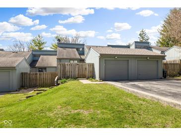 Exterior view of the condo building with a two-car garage and well-maintained green lawn on a sunny day at 652 Blossom Dr, Avon, IN 46123