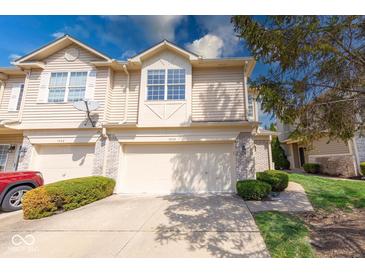 Inviting townhouse featuring a two-car garage, charming landscaping, and stone facade accents at 1045 Evening Shade Cir, Beech Grove, IN 46107
