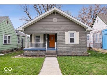 Charming bungalow featuring a textured gray exterior, orange front door, and a cozy front porch at 1310 N Chester Ave, Indianapolis, IN 46201