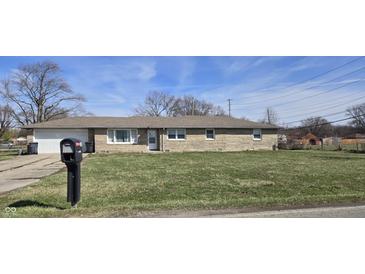 Ranch home with a stone facade, attached garage, and well-maintained front lawn at 3002 W 53Rd St, Anderson, IN 46011