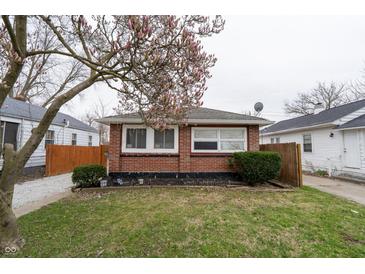 Cozy brick home featuring a well-maintained lawn and a mature tree with blossoming flowers in a peaceful residential neighborhood at 4711 East 21St St, Indianapolis, IN 46218