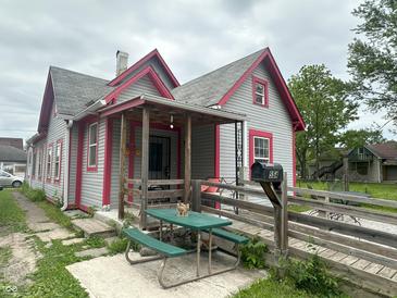 Charming home with gray siding, red trim, covered porch, wooden ramp, and picnic table at 554 N Tacoma Ave, Indianapolis, IN 46201