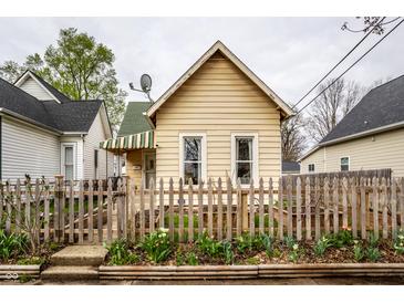 Charming exterior featuring a peaked roof, picket fence and garden beds with tulips at 902 Villa Ave, Indianapolis, IN 46203