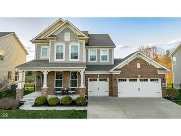 Charming two-story home with a brick and gray facade, a covered front porch, and a two-car garage at 15958 Oakhurst Ln, Fishers, IN 46040