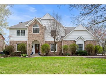 Charming brick and white two-story home with well-manicured lawn and lush landscaping at 325 W Greyhound Pass, Carmel, IN 46032