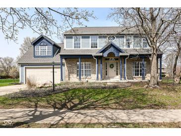Charming two-story home with brick facade, blue trim, a welcoming front porch, and manicured landscaping at 10944 Echo Trl, Indianapolis, IN 46236