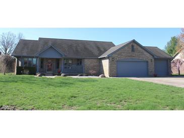 Charming single-story brick home with an attached three-car garage and covered porch situated on a well-manicured lawn at 1915 Barbie Ct, Franklin, IN 46131