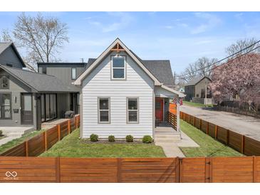Charming home featuring a fenced yard, freshly cut grass, and a quaint front porch with bright orange door at 358 Terrace Ave, Indianapolis, IN 46225