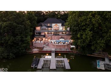 Luxury home featuring a private pool, dock, lake access, and elegant design nestled in a wooded landscape at dusk at 219 Surrey Hill, Noblesville, IN 46062