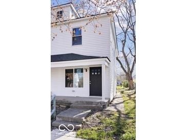 Charming two-story home featuring a black front door, white siding, and a welcoming front porch at 243 N Tacoma Ave, Indianapolis, IN 46201