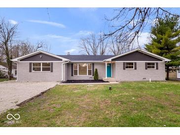 Charming single-story home featuring a gray brick exterior, a neatly landscaped front yard, and a bright turquoise front door at 322 S Boehning St, Indianapolis, IN 46219