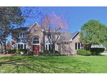 Attractive brick home with a well-manicured lawn and mature trees on a sunny day at 5139 Kingswood Dr, Carmel, IN 46033