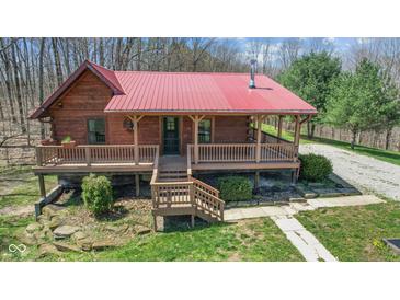 Charming log cabin with a red roof and inviting covered porch at 6351 Dixon Rd, Columbus, IN 47201
