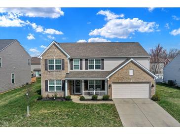 Two-story home featuring a brick and vinyl facade, attached two-car garage, and a charming covered front porch at 1279 Windswept Dr, Greenwood, IN 46143