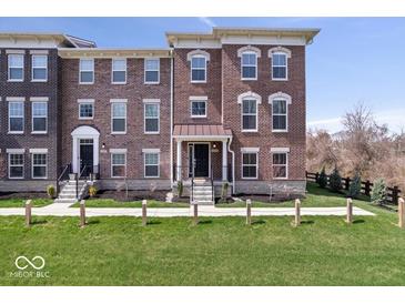 Charming brick townhome featuring a well-manicured lawn and inviting front entrance at 13833 Tender Dr, Carmel, IN 46032