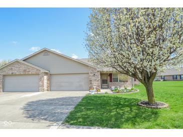 Charming single-story home featuring a well-manicured lawn, flowerbeds, and an attached two-car garage at 3925 Oak Harbor Ln, Indianapolis, IN 46237