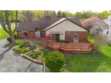 Beautifully landscaped backyard featuring a wooden deck, mature trees, and charming details at 6141 Madison Ave, Indianapolis, IN 46227