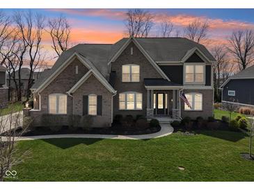 Elegant home with brick facade, well-kept lawn, and professionally landscaped garden beds at 14747 Harvest Glen S Blvd, Fishers, IN 46037