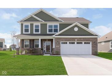 Two-story home featuring a brick facade and green siding, plus a well-manicured lawn and two car garage at 1695 Jackson St, Fortville, IN 46040