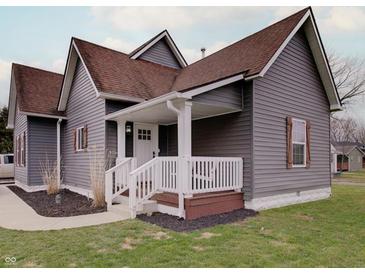 Charming home with gray siding, brown roof, white trim, covered porch, and a well-manicured lawn at 501 W Pearl St, Trafalgar, IN 46181