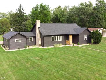 Beautifully renovated one-story home with a lush green lawn and dark siding at 6555 Michigan Rd, Indianapolis, IN 46268