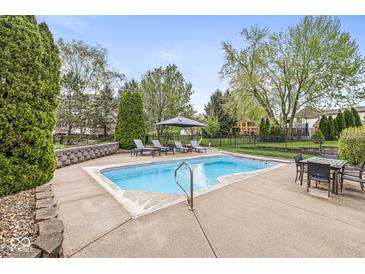 Backyard pool area complete with lounge seating, dining table, mature landscaping, and recreation space at 7259 Josiah Ct, Indianapolis, IN 46259