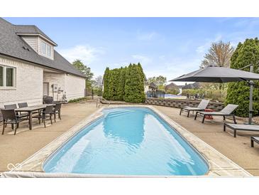 Inviting backyard pool area with lounge seating, mature landscaping, and outdoor dining space on a sunny day at 7259 Josiah Ct, Indianapolis, IN 46259