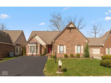 Charming brick home featuring a well-manicured lawn, red door, and inviting curb appeal at 9544 Huntington Ln, Indianapolis, IN 46260