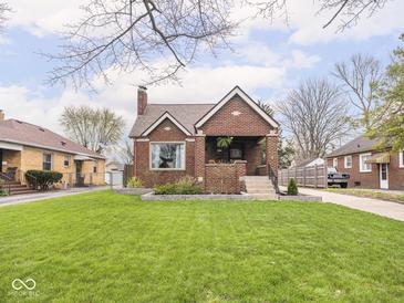 Charming brick home featuring a well-manicured lawn, landscaped garden beds, and a cozy covered front porch at 1139 N Butler Ave, Indianapolis, IN 46219