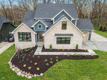 Striking two-story home featuring a stone facade, blue siding accents, and a well manicured front yard at 11640 Ansley Ct, Zionsville, IN 46077
