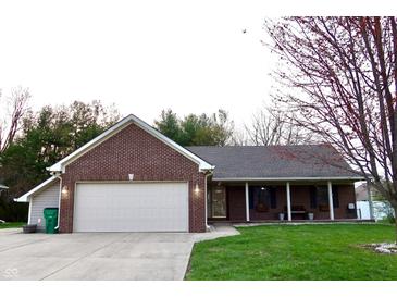 Charming brick home featuring an attached garage, well-manicured lawn, and covered front porch at 13116 N Departure W Blvd, Camby, IN 46113
