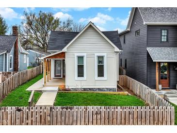 Charming home featuring a freshly-cut lawn, a decorative picket fence, and a cozy porch entryway at 305 Sanders St, Indianapolis, IN 46225