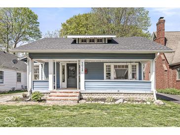 Inviting home with a covered porch, classic architecture, and a well-manicured lawn at 5028 Graceland Ave, Indianapolis, IN 46208