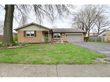 Charming brick home featuring an attached garage, manicured lawn, and mature landscaping at 218 Demarest Dr, Indianapolis, IN 46214
