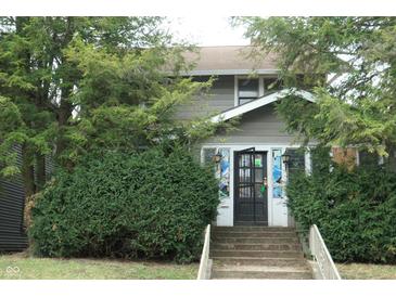 Charming home exterior with mature trees and greenery in the front yard at 4925 E New York St, Indianapolis, IN 46201
