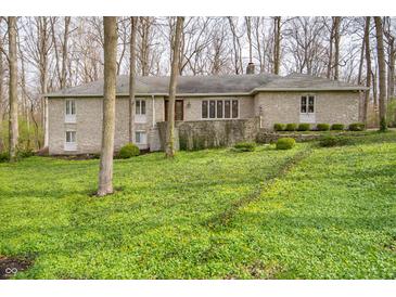 Stone-clad home with a low-pitched roof surrounded by lush, green ground cover and mature trees at 5918 Camelback Ct, Indianapolis, IN 46250