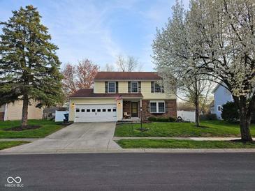 Charming two-story home with a well-manicured lawn and attached garage with a concrete driveway at 7809 Bryden Dr, Fishers, IN 46038