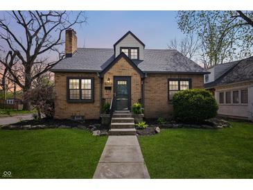 Charming brick home featuring a well-manicured lawn, complemented by elegant landscaping and a welcoming entrance at 1025 E 60Th St, Indianapolis, IN 46220