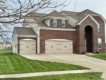 Charming brick two-story home boasts an attached three-car garage and a well-manicured front lawn at 11958 Logan Hunter Trl, Noblesville, IN 46060