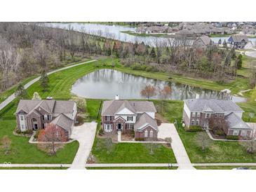 Aerial view of a brick home with a large pond, mature trees, and well-manicured lawn in a desirable community at 12030 Auburn Creek, Zionsville, IN 46077