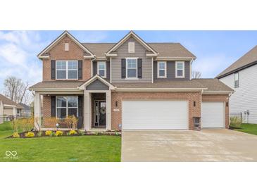 Charming two-story brick home featuring a two-car garage and a well-manicured lawn and tasteful landscaping at 2736 Victory Dr, Columbus, IN 47203
