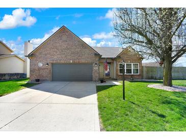Charming brick home with attached garage and well-maintained front lawn at 701 Downing Dr, Greenwood, IN 46143