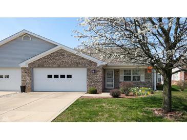 Charming brick home featuring an attached garage, well-maintained lawn, and lovely flowering tree in the front yard at 8142 Bentley Farms Dr, Indianapolis, IN 46259