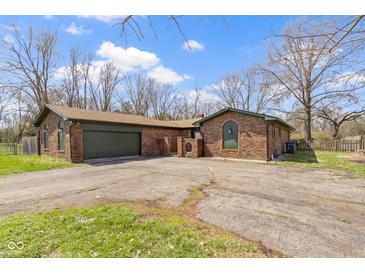 Brick home featuring attached garage, large driveway, beautiful architectural details, and mature trees at 5344 Tincher Rd, Indianapolis, IN 46221