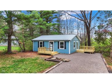 Charming blue home featuring a metal roof, dark shutters, and newly constructed wooden porches in a wooded lot at 7469 Lion Dr, Nineveh, IN 46164