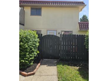 Charming townhome featuring tan siding, a brown tile roof and enclosed by a decorative black fence at 2804 Paso Del Norte Dr, Indianapolis, IN 46227