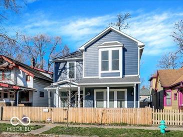 Charming two-story home featuring a blue exterior, white trim, fenced yard, and a welcoming front porch at 46 N Denny St, Indianapolis, IN 46201