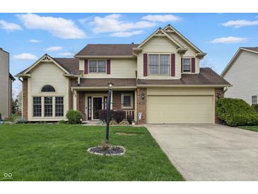Classic two-story house featuring a manicured lawn, attached garage, and inviting entrance with a lamppost at 5710 Dapple Trce, Indianapolis, IN 46228
