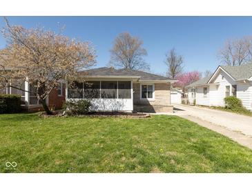 Charming stone home featuring a cozy screened-in porch and well-manicured lawn at 6120 Norwaldo Ave, Indianapolis, IN 46220